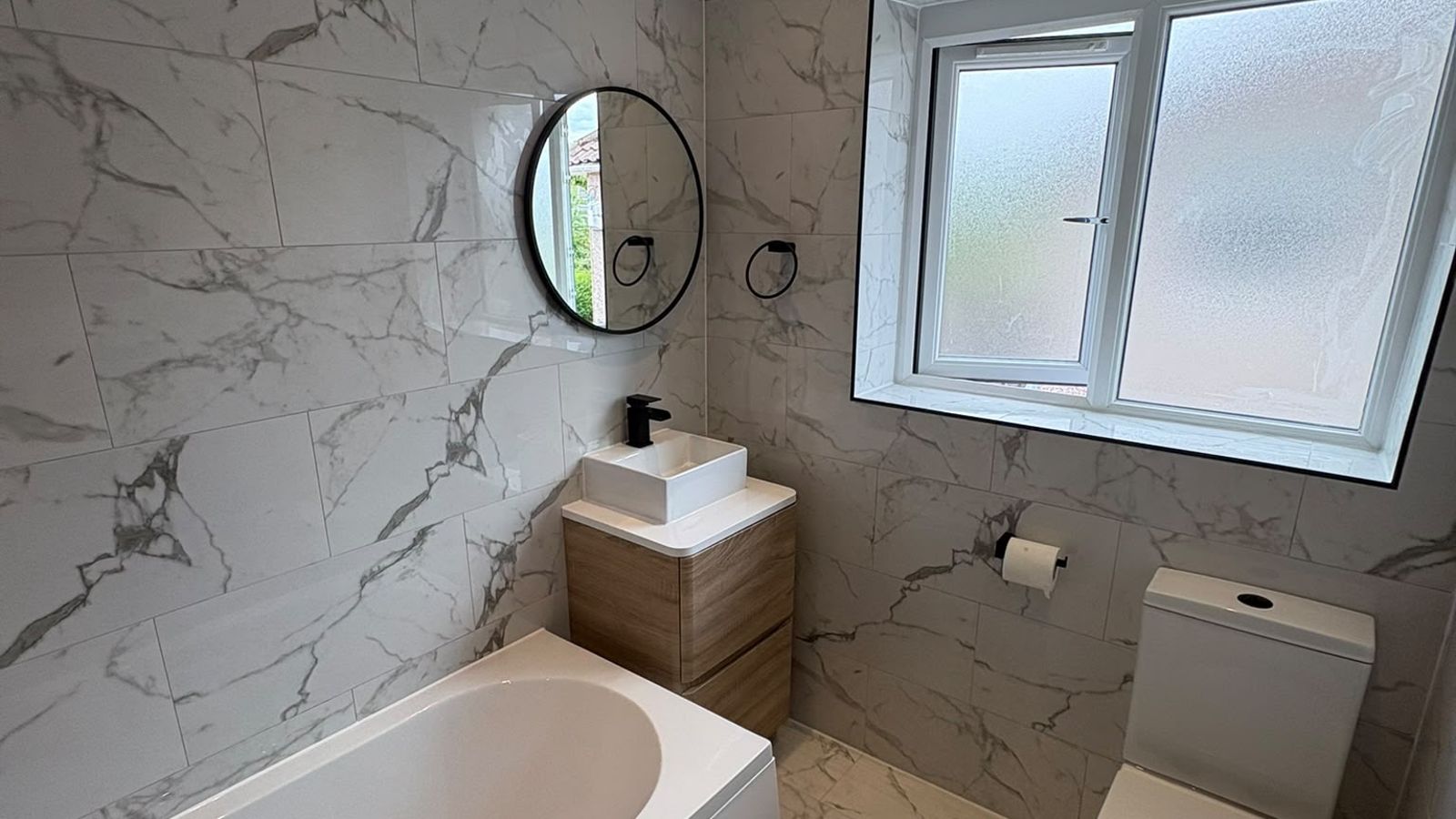 Finished marble-tiled bathroom with bath, vanity and window