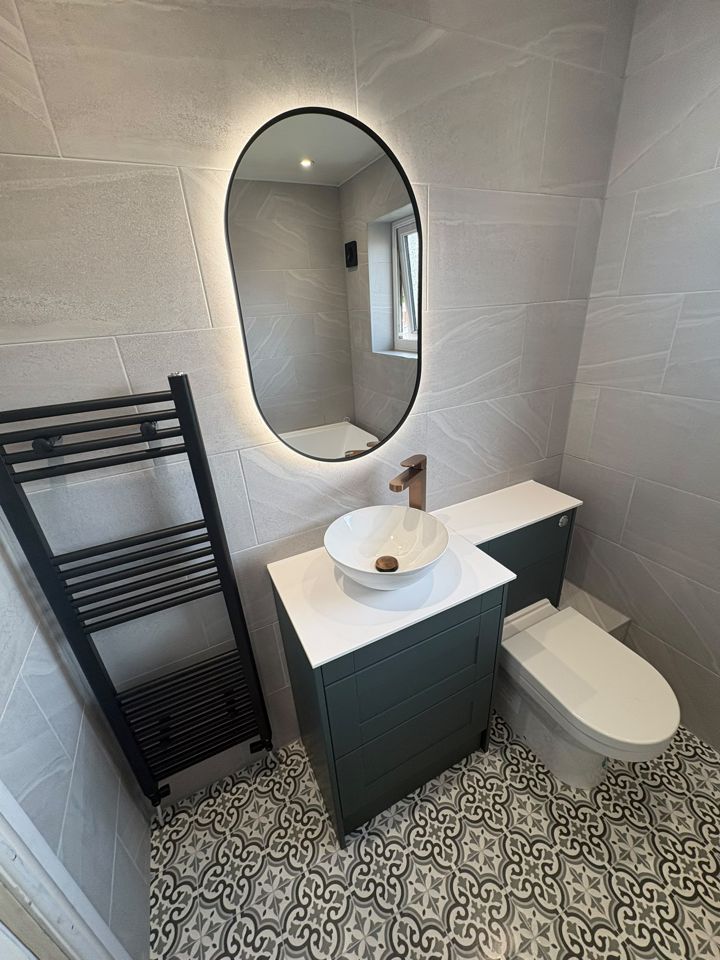 Bathroom with illuminated mirror, green vanity and patterned floor