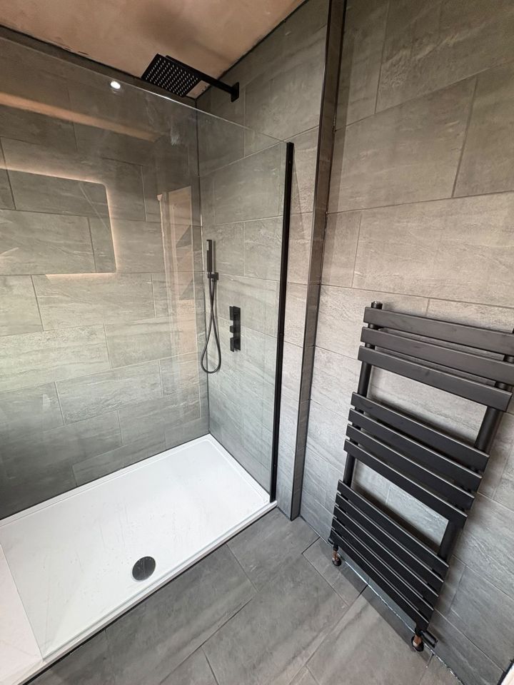 Walk-in shower with black fittings and grey tiles