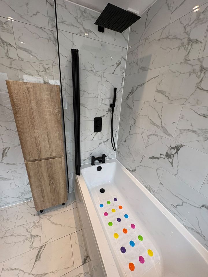 Marble-effect bathroom with bath and tall wooden cabinet