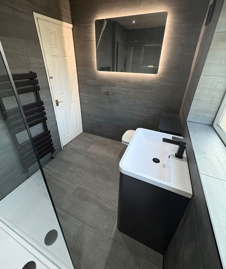 Bathroom with dark vanity, backlit mirror and black heated towel rail
